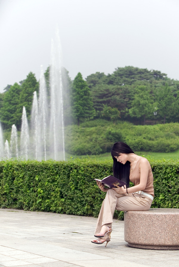 坐在公园石头上看书的美女图片
