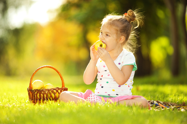 草地上吃苹果的小女孩图片