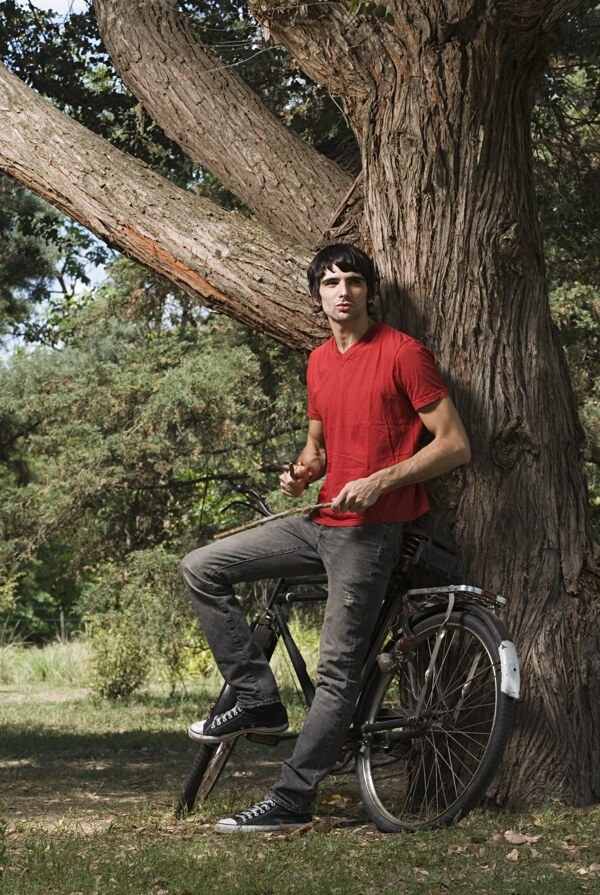 拿着木棍靠在自行车上的男人图片