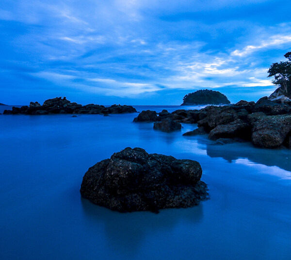 岩石日落海滩蓝色自然风景摄影图