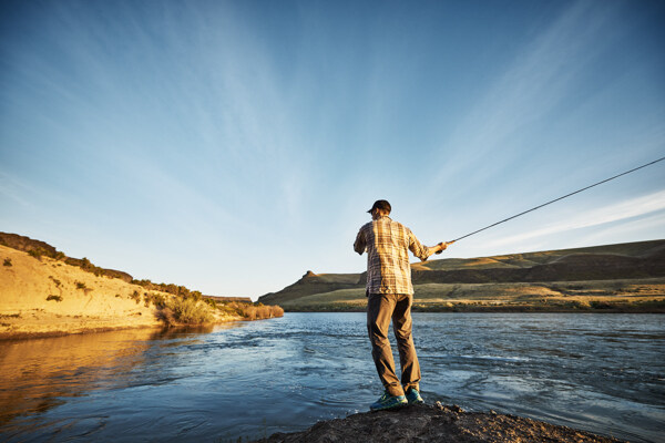 站在溪边甩竿钓鱼的男人