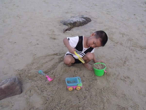 沙滩上玩沙子的小孩图片
